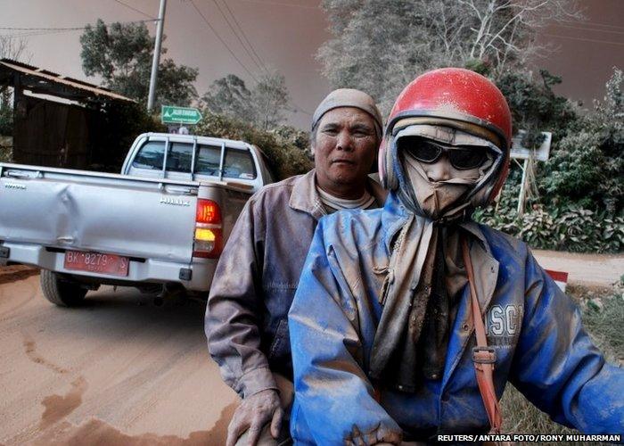 Residents with faces covered in ash ride on a motorcycle as Mount Sinabung volcano erupts, in Sukandebi village in Karo Regency, Indonesia's North Sumatra province, June 13, 2015