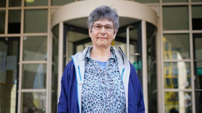 Diana Warner, wearing a blue blouse and coat, outside court.