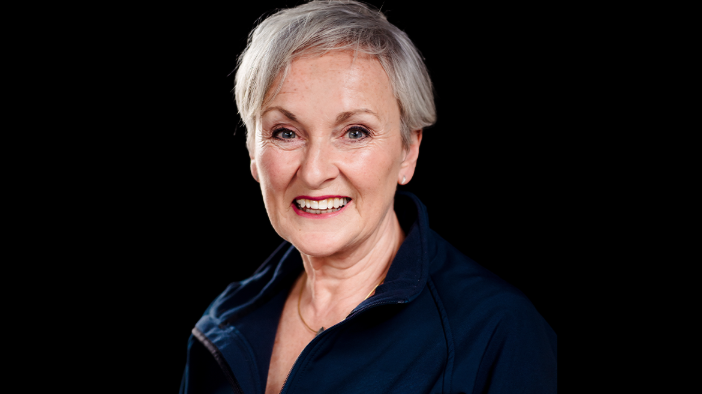 Siobhan Casey has short grey hair and is wearing a dark blue top, pictured against a white background. 