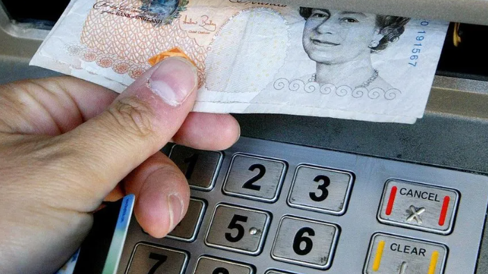 A hand taking money from a cash machine