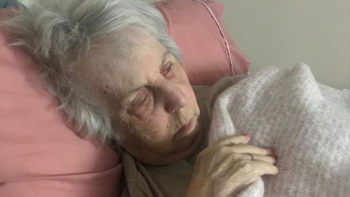 Vivian Harris lies on a bed clutching a blanket while looking frail