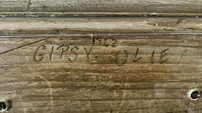 A wooden fireplace with the names Gipsy and Olie and the year 1942 carved in.