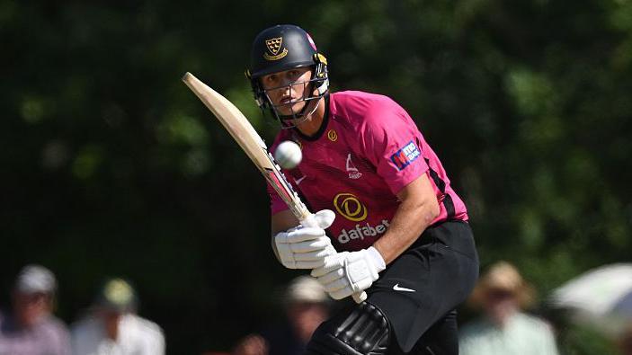 George Thomas, in pink Sussex shirt, looks at the ball after playing a shot during the Metro Bank One Day Cup match between Sussex Sharks and Essex