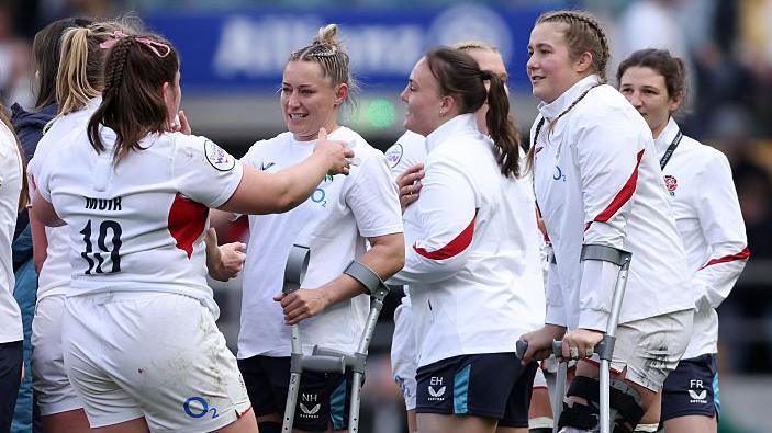 Morwenna Talling and Natasha Hunt on the pitch on crutches