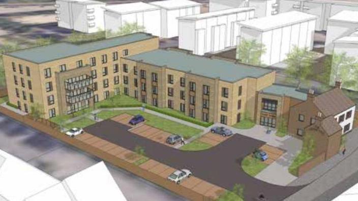 A CAD drawing of a the Cherry Tree pub site in Peterborough. The old two-storey pub building is on the right and extending beyond it is a three storey block. At right angles to the three-storey block is a four-storey block. In front of the blocks is an L-shaped piece of grass and a car park.