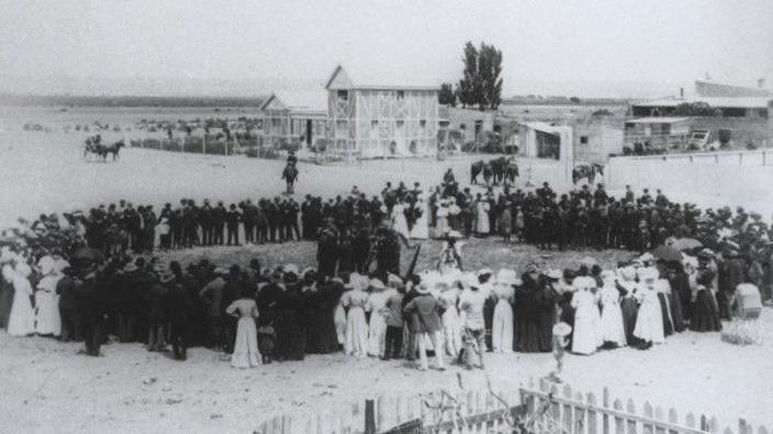 Llun du a gwyn yn dangos grŵp mawr o bobl yn sefyll mewn cylch yn yr awyr agored.