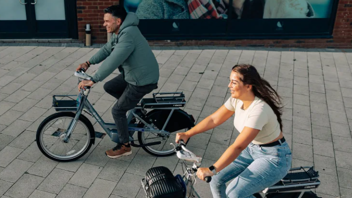 Two people riding Beryly e-bikes on an urban street.