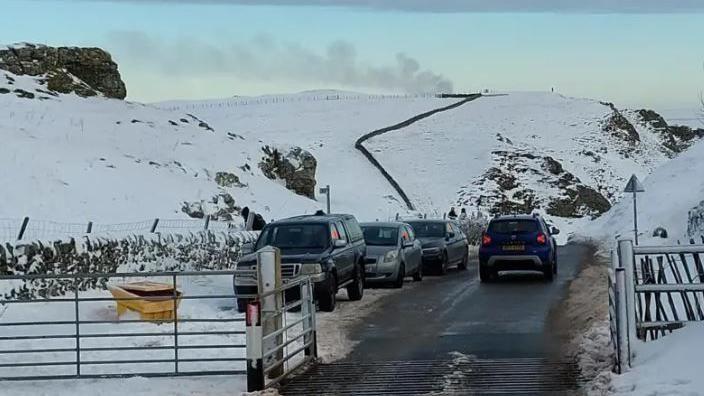 Cars parked on a clearway at Winnats Pass. There is snow on the ground