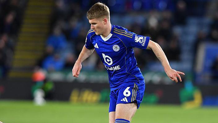 Jordan James in a blue Leicester City kit running with the ball during a game