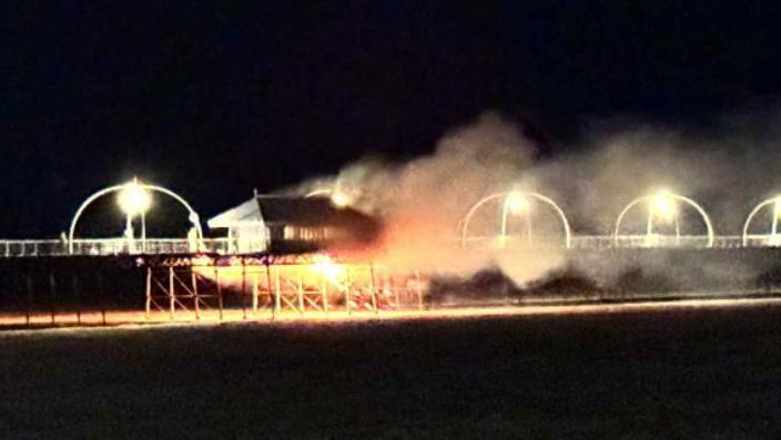 Smoke and fire billows from Southport Pier surrounded by black sky.
