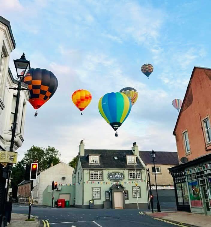 Brightly coloured hot air balloons float above the Weavers pub, which is an idyllic mint green building with coloured bunting.