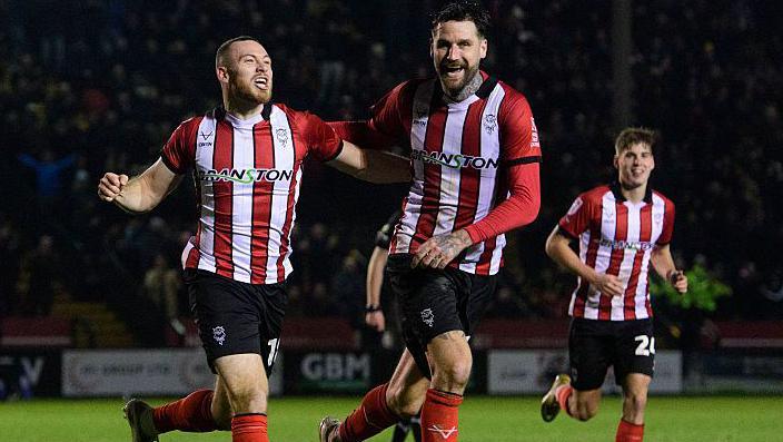 Lincoln City's Ben House, left, celebrates scoring his side's third goal with team-mate Sonny Bradley
