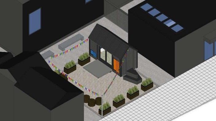 The image shows a 3D depiction of the proposed building site, with some plants around the building, colourful bunting and what looks like a small studio. Two grey benches can be seen on the right-hand-side of the building.