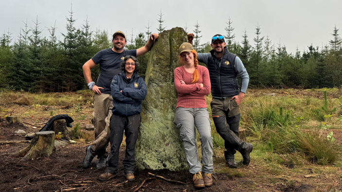 Time team stood leaning on Farley Moor standing stone