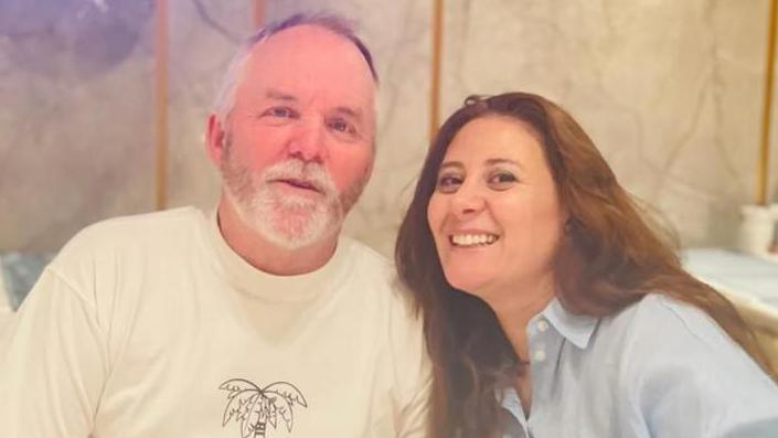 William and Nadia McCullough smiling while looking at the camera - he is wearing a while T-shirt while she has a blue top on 