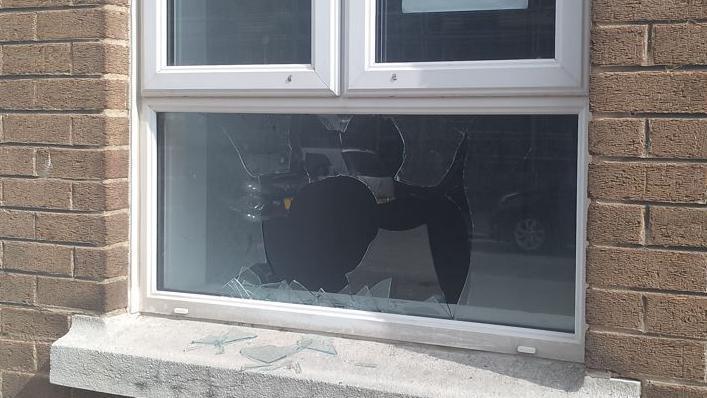 A close up of a broken window - showing shards of glass on a window sill