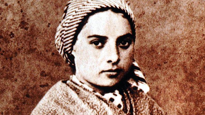 An portrait in greyscale of St Bernadette - she is a young girl at the time and is wearing a headscarf and shawl