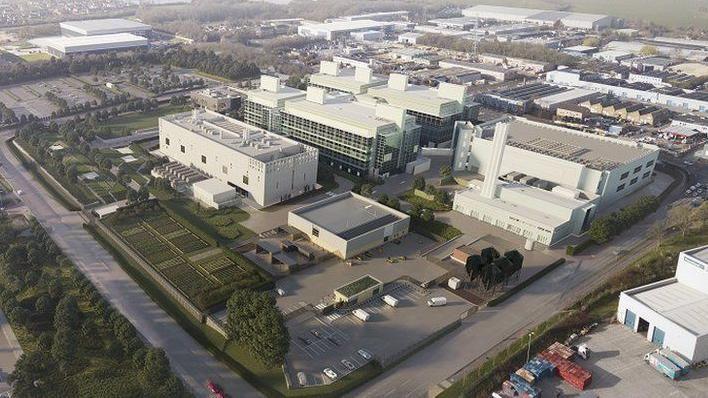 An artist's impression of the aerial view of how the project would look. It is a large site with several big, white industrial buildings. It is based on a sprawling industrial estate and has trees and grass on one side.