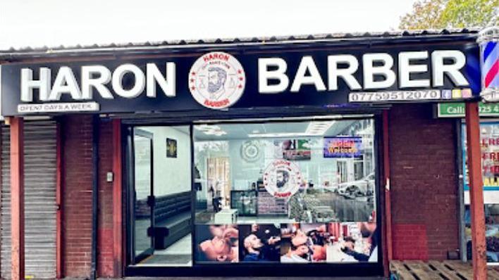 The outside of Haron Barber with sign and shop window.