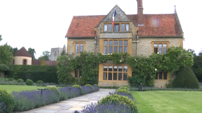 Le Manoir aux Quat'Saisons - a 15th century manor house with lawns and lavender beds in front, with a French flag flying from above the upstairs window.