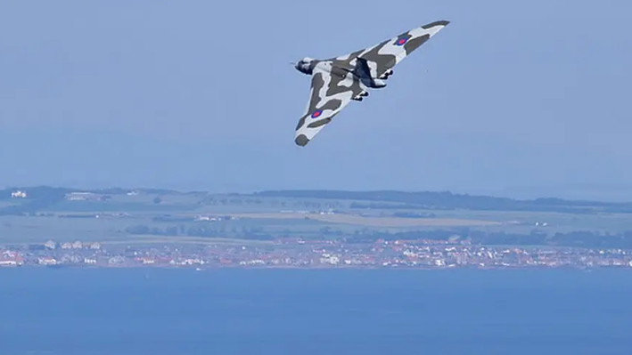 XH558 flying over a seaside town