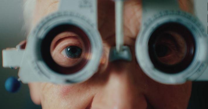 Close up image of an elderly man having his eyes tested by an optometrist