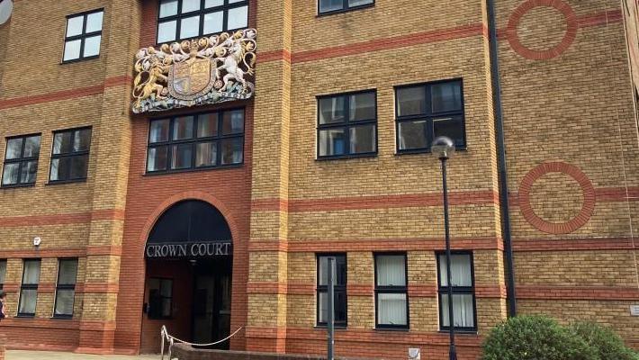 St Albans Crown Court: a brown-and-red-bricked building with black-framed windows. The words "CROWN COURT" are written above the entrance in gold.