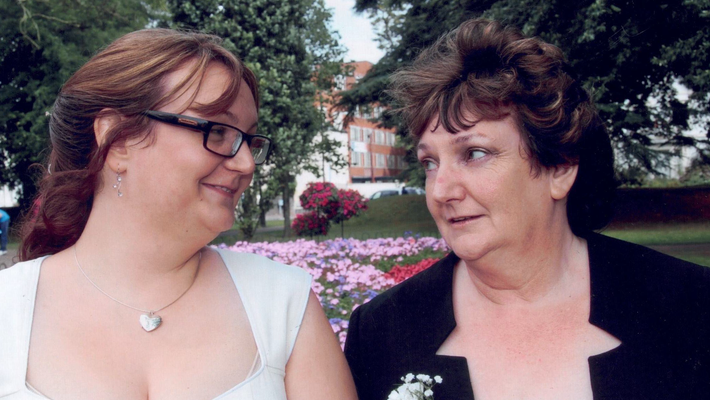 June Fox-Roberts with daughter Abi Sheppard on her wedding day, pictured in front of a lawn with flowerbeds