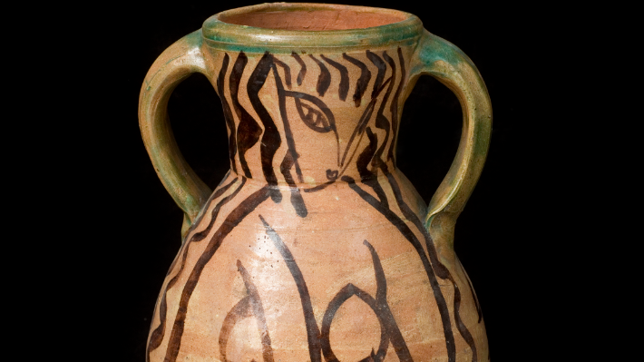 A brown urn with two handles, glazed with a black abstract pattern, the work of Bloomsbury group artist Duncan Grant