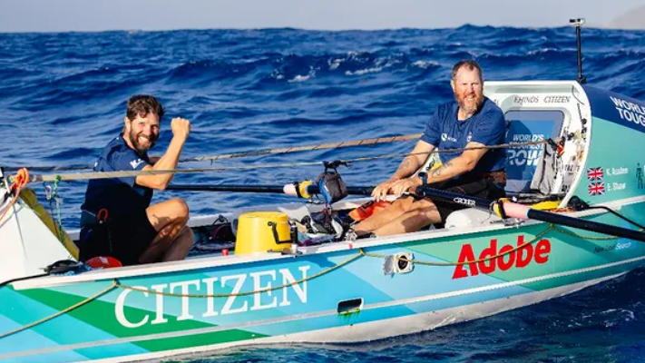 Karl Austen and Ed Shaw in there rowing boat smiling at the camera. 