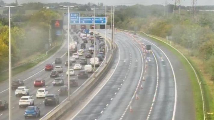 CCTV still image of traffic jams on one side of a motorway and four empty lanes on the other side. It appears to be raining.