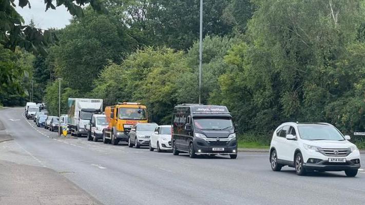 A queue of traffic on the road next to Dalscone Farm.