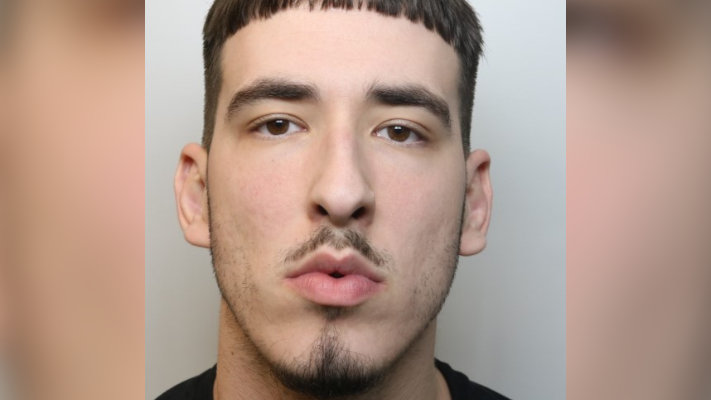 A mugshot of Oskar Krzeszewski. He has a small moustache and goatee and is wearing a black top.