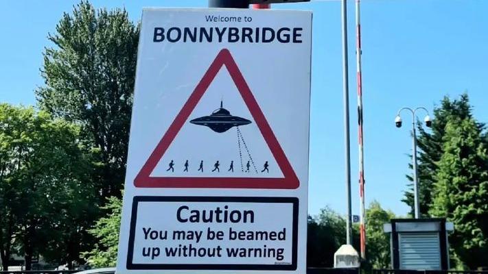 A sign in Bonnybridge which shows a UFO zapping tiny humas. The sign says Caution: You may be beamed up without warning