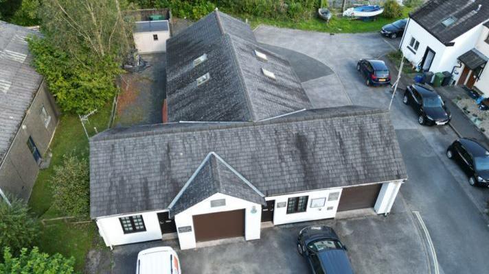 An aerial image of the current Coniston Mountain Rescue Team base on Old Furness road. The building is in a T-shape and has some garage doors to the front and white rendering.