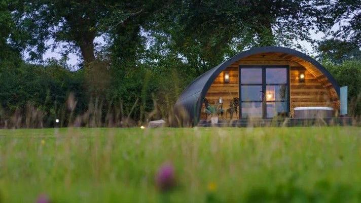 An artist impression of a glamping pod on a former watercress farm. There are trees behind the pod.