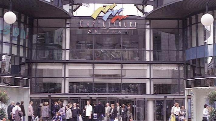 Castlecourt centre from the outside with its yellow, blue and red logo. Shoppers are pictured going in and out of the centre.