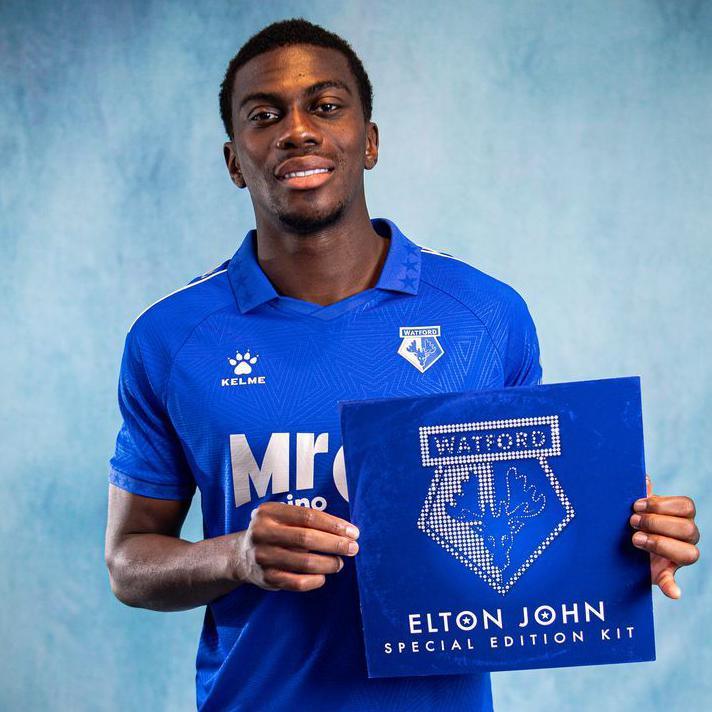 A man is holding a picture of the Watford football cub logo