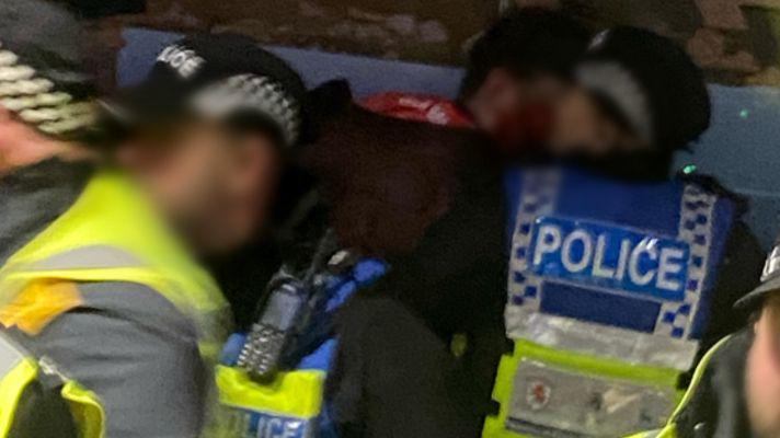 User-submitted blurry image of police officers with blurred faces in a crowd.