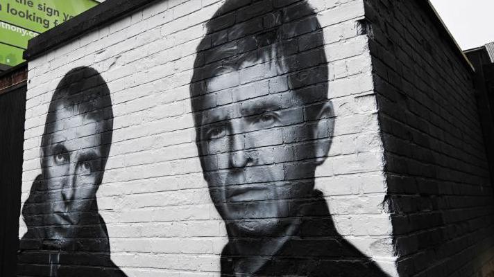 A black and white mural on a brick wall depicting Liam Gallagher (L) and Noel Gallagher (R) 