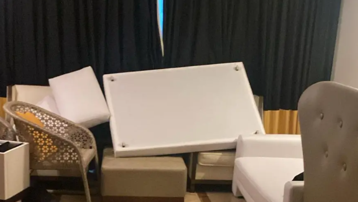 Assorted furniture propped up against the windows of the Holmes family's hotel room in Jamaica. There are beds, sofas and chairs.