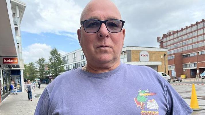 Steve Chapman, wearing dark glasses and a blue T-shirt, standing in front of the cordoned off area where the clean-up is underway.