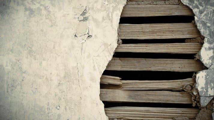 Close up of lath and plaster showing strips of wood behind broken plaster