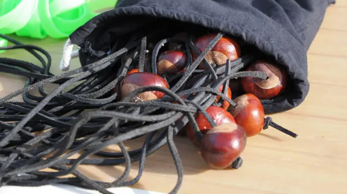 Conkers spill from a black bag. Each are strung with black laces