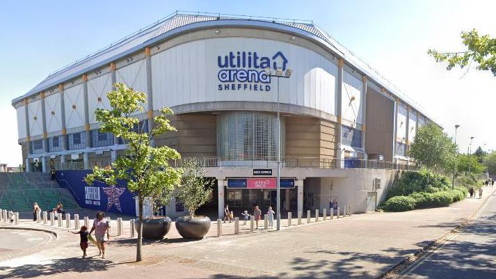 A large events arena with trees and bollards outside. A sign on the building reads Utilita Arena Sheffield