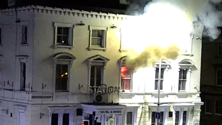 A fire can be seen through a window at the Station Hotel in Gloucester. Smoke is billowing out of the window.