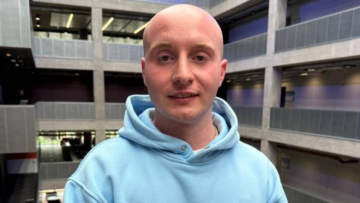 A young bald man wearing a light blue hoody.