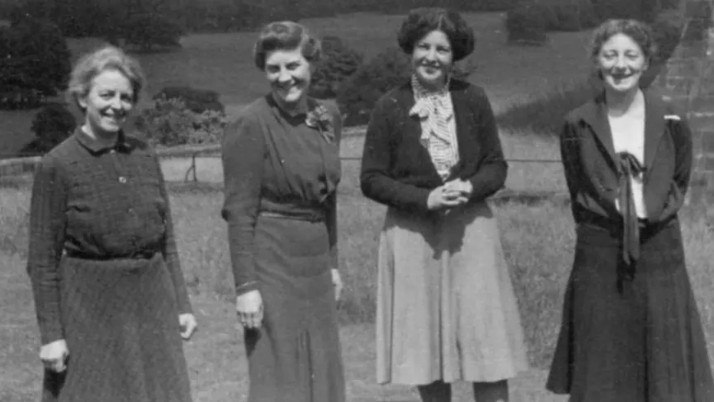 Four middle aged women in a row next to the castle walls