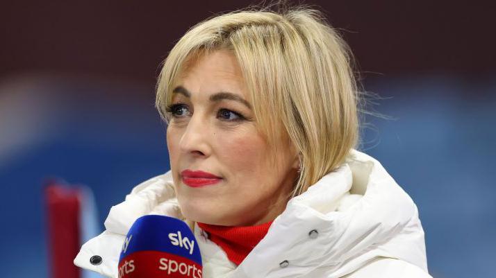 Kelly Cates presenting on Sky Sports. She has blonde hair, and is wearing a white puffa jacket