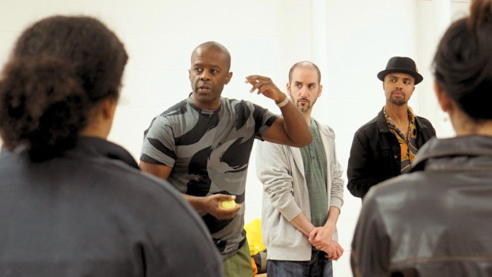 Adrian Lester leading a workshop with fellow artists standing around him